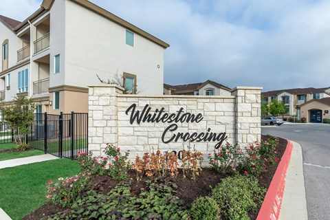 A sign that says "Whitestone Crossing" in front of a building.