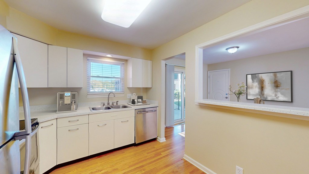 A kitchen with white cabinets and a wooden floor.