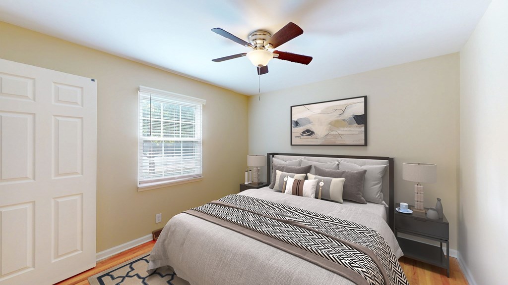 A bedroom with a bed, nightstand, and a ceiling fan.
