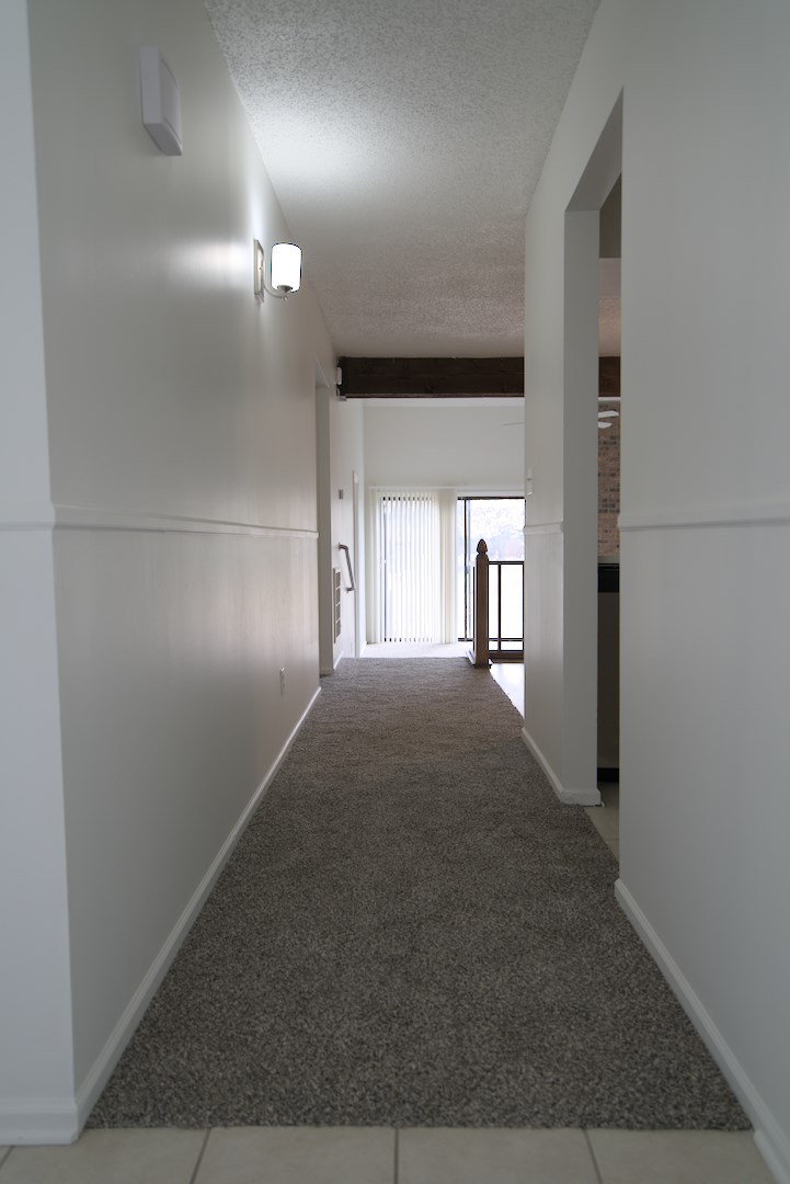 A long hallway with a carpeted floor and white walls.