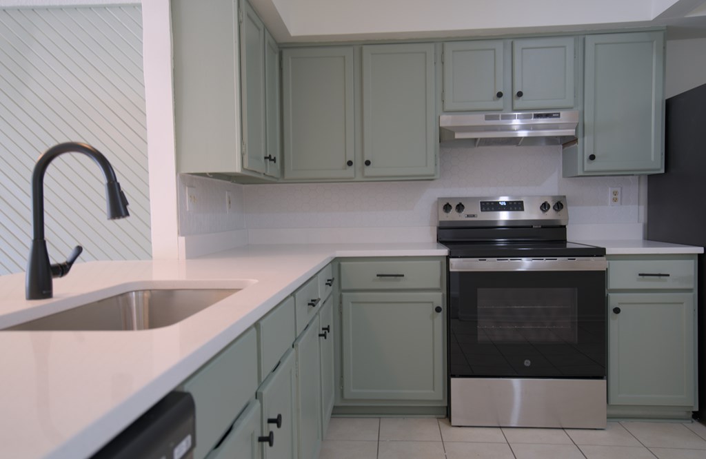 A kitchen with a sink, stove, and cabinets.