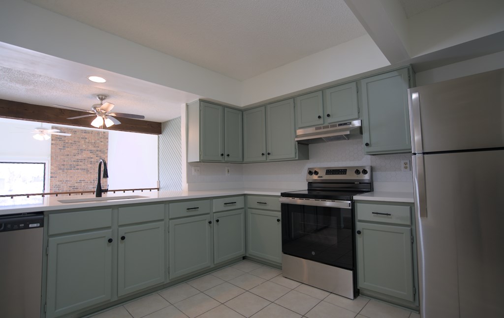 A kitchen with green cabinets and stainless steel appliances.
