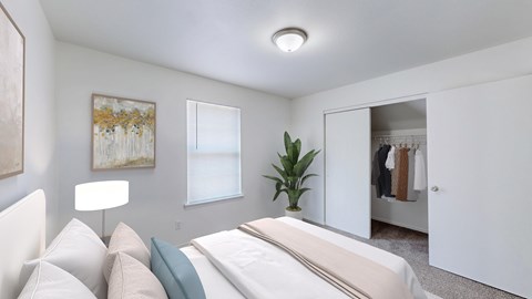 A bedroom with a bed, a lamp, a plant, and a painting on the wall.