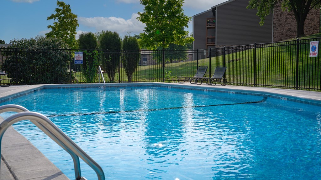 A pool with a metal railing in front of it.