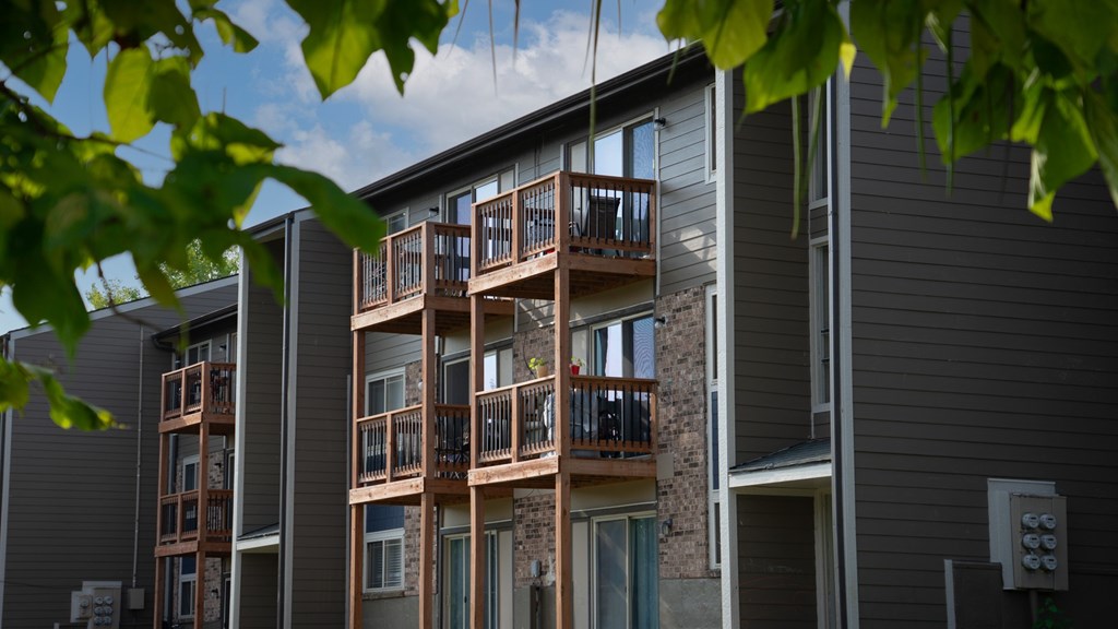 A building with a balcony and a tree in front of it.