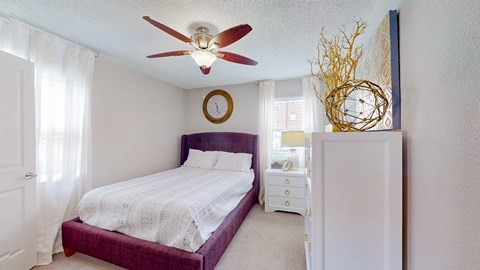 A bedroom with a purple bed and a white dresser.