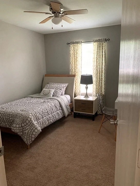 a small bedroom with a bed and a ceiling fan