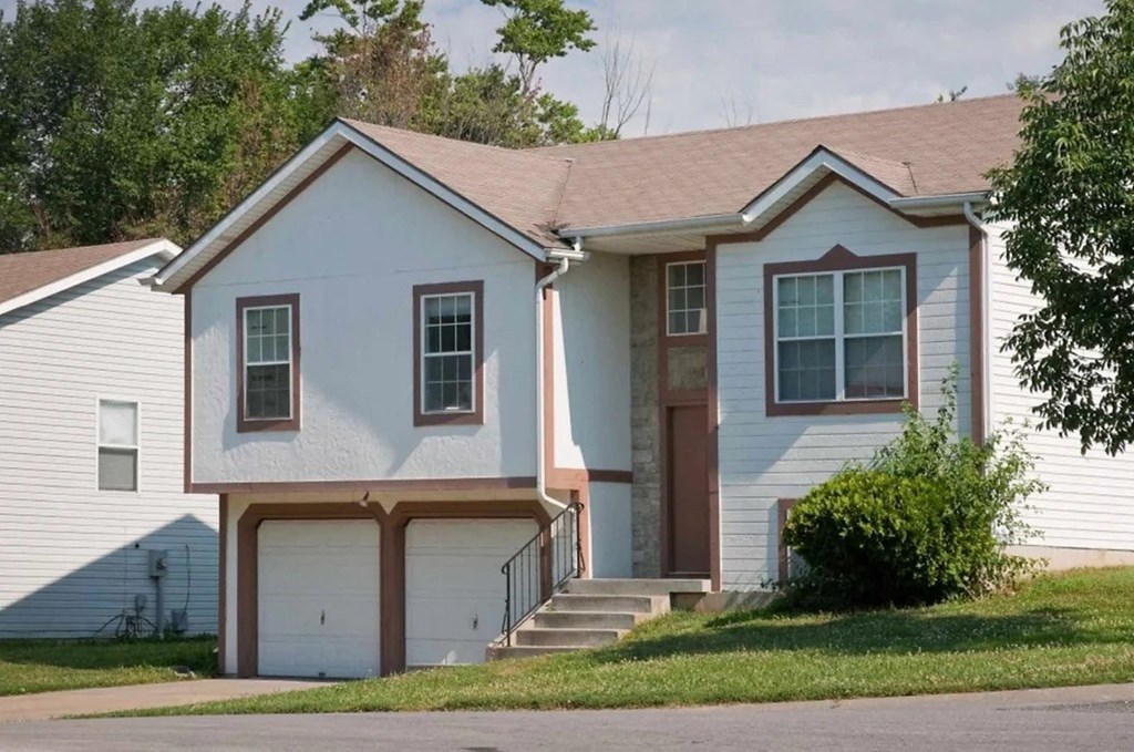 a white house with a garage door and stairs