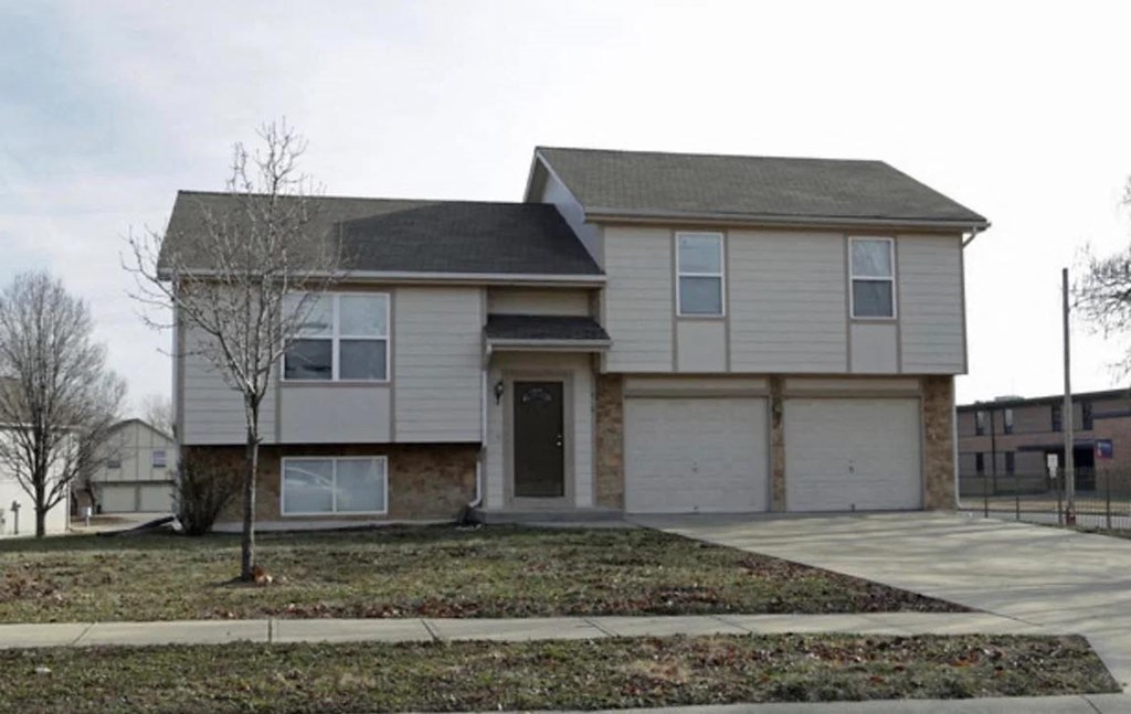 the front of a tan and brown house with a sidewalk