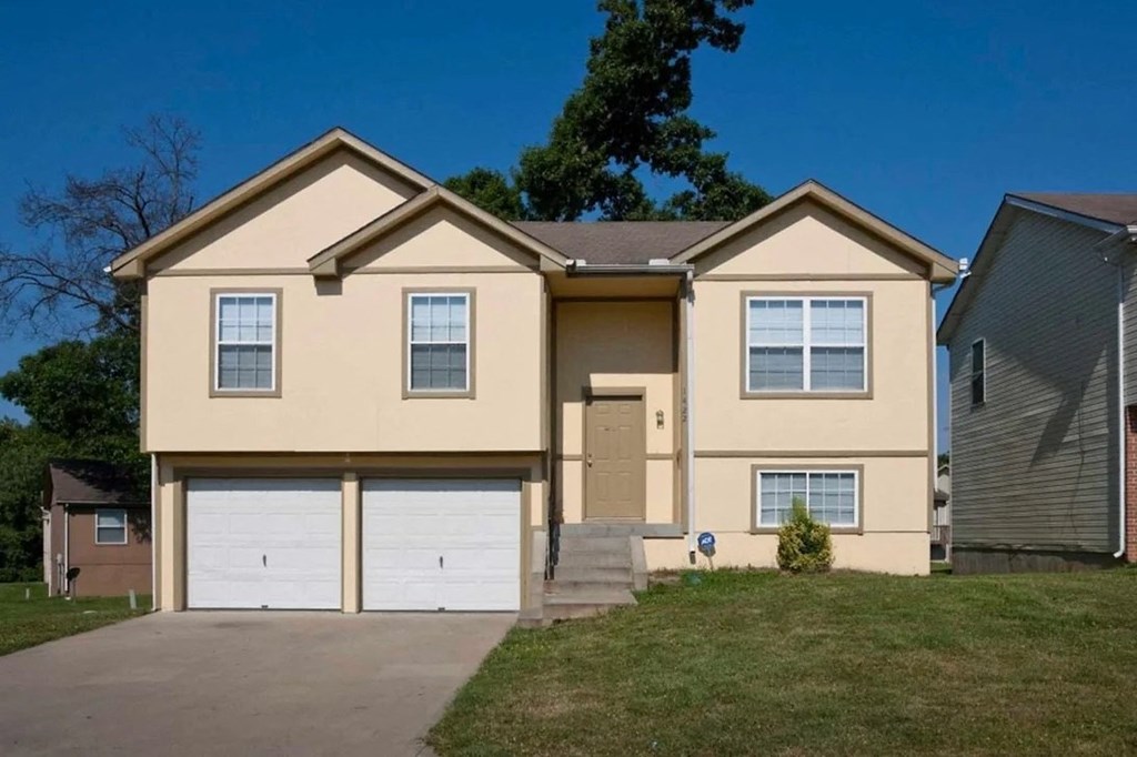 a tan house with a driveway and a lawn