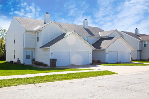a white house with two garage doors and a sidewalk