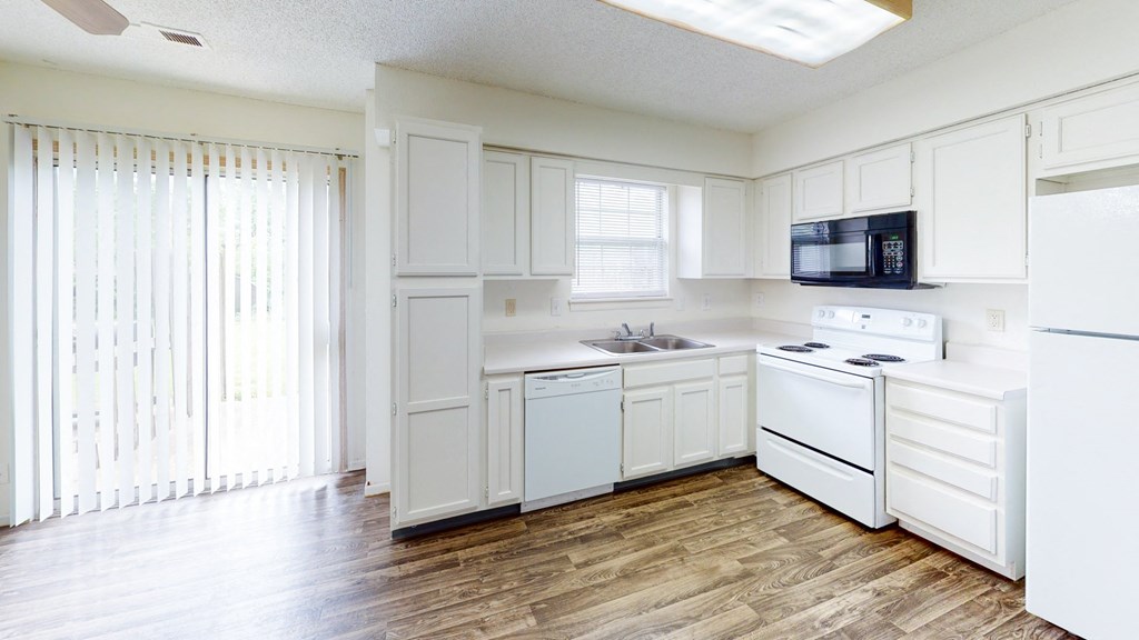 an empty kitchen with white cabinets and white appliances