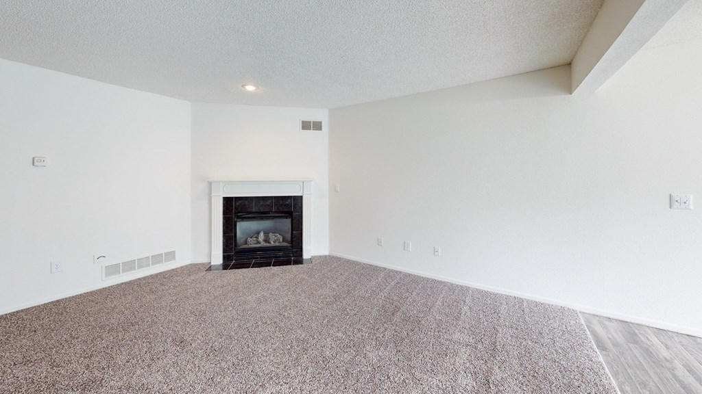 an empty living room with a fireplace and white walls