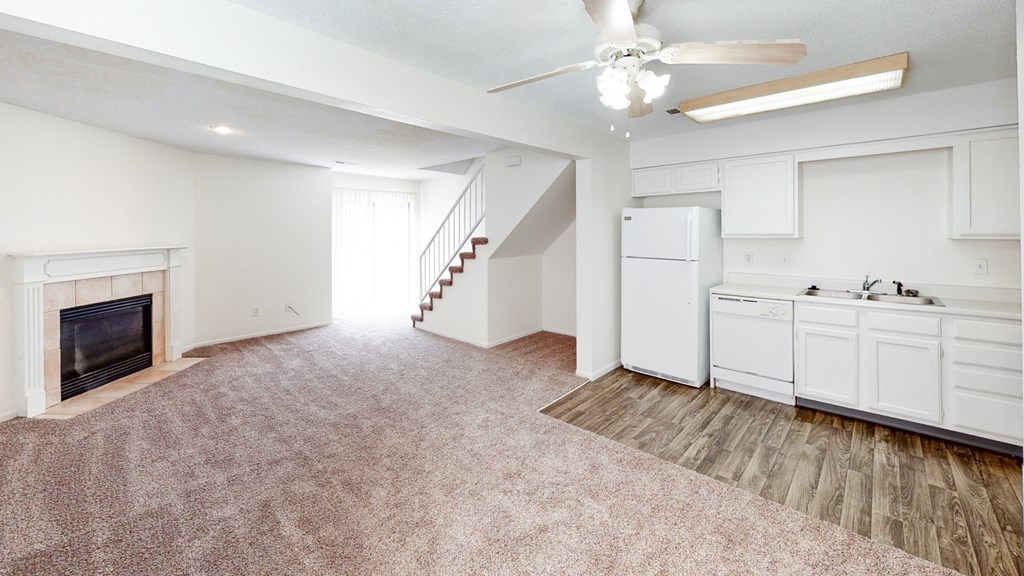 an empty living room with a fireplace and a kitchen