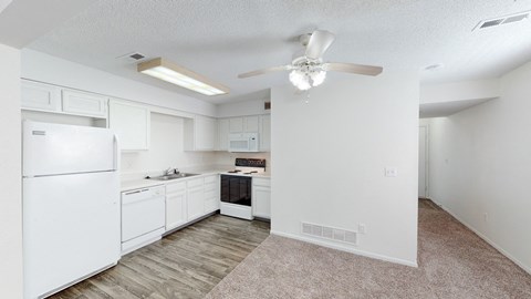 an empty kitchen with white cabinets and a ceiling fan