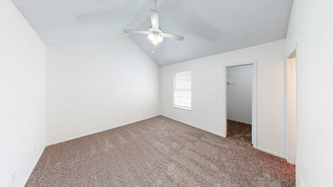 an empty room with carpet and a ceiling fan