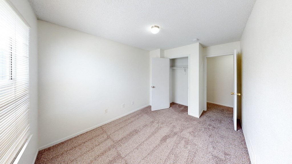 a spacious living room with carpet and white walls