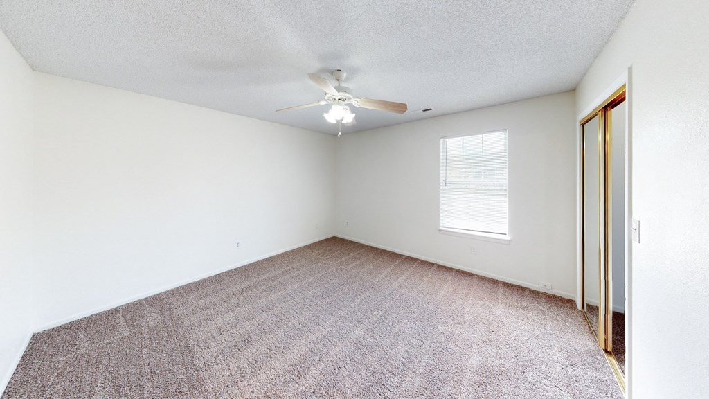 an empty room with a ceiling fan and a window