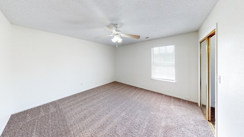 an empty room with a ceiling fan and a window