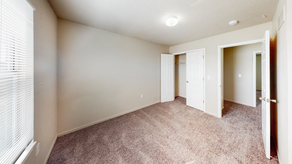 an empty room with a door to a closet and a window