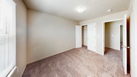 an empty room with a door to a closet and a window