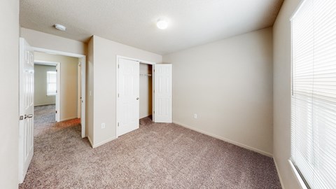 an empty living room with a door to a closet and a window