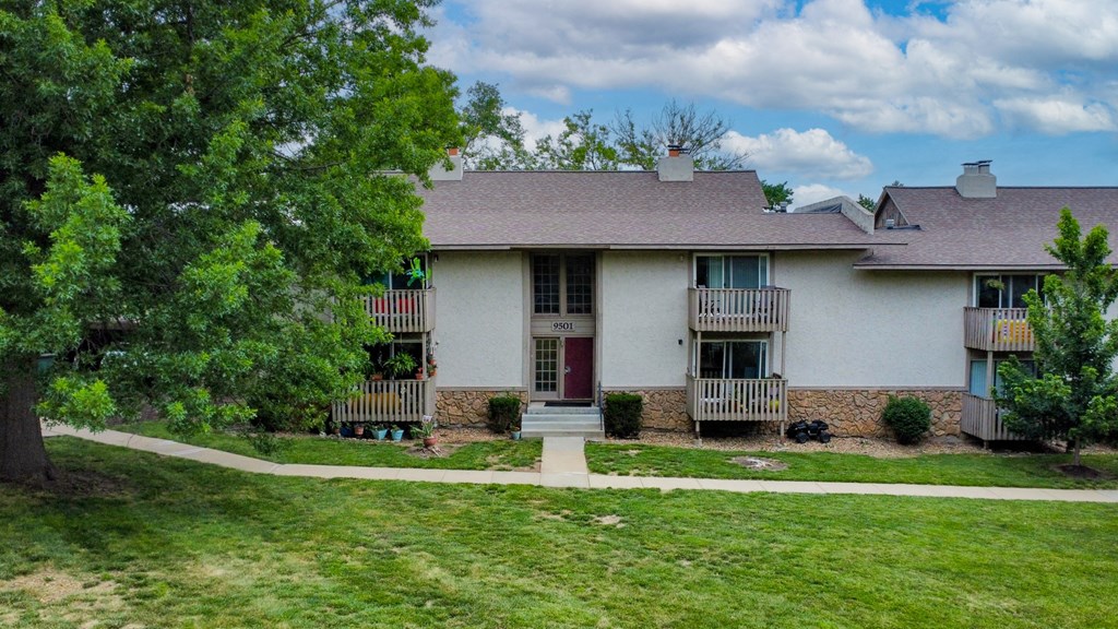 a white house with two balconies and a grassy yard