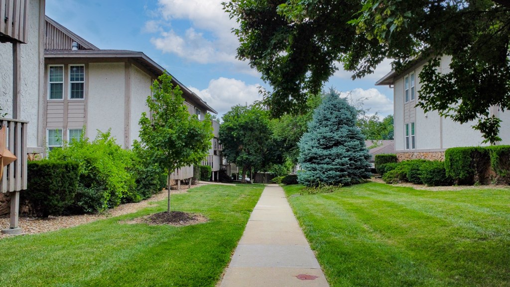 a sidewalk in front of houses on a green lawn