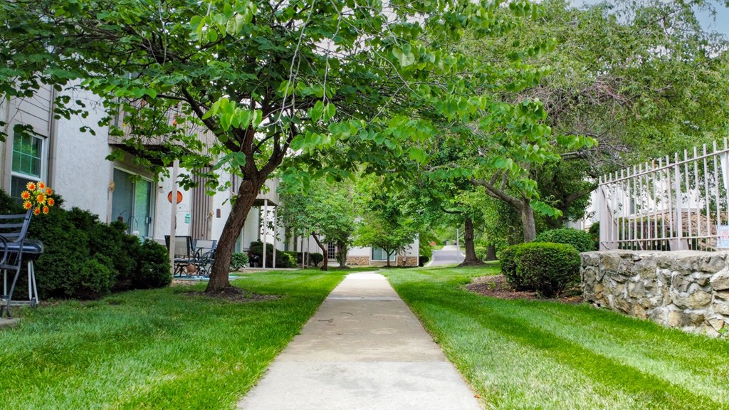 a tree lined sidewalk in front of a house