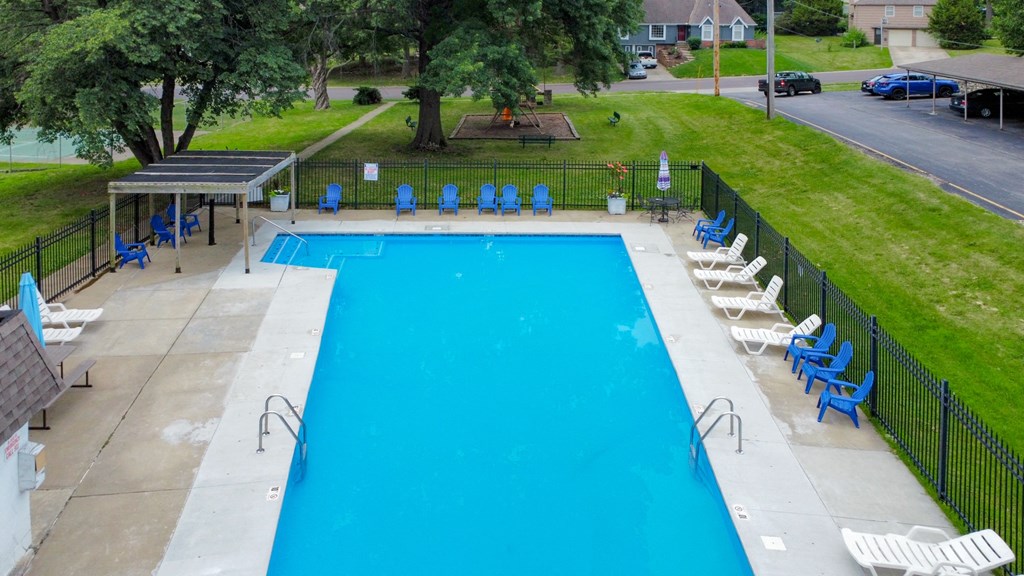 a swimming pool with chairs and a fence around it