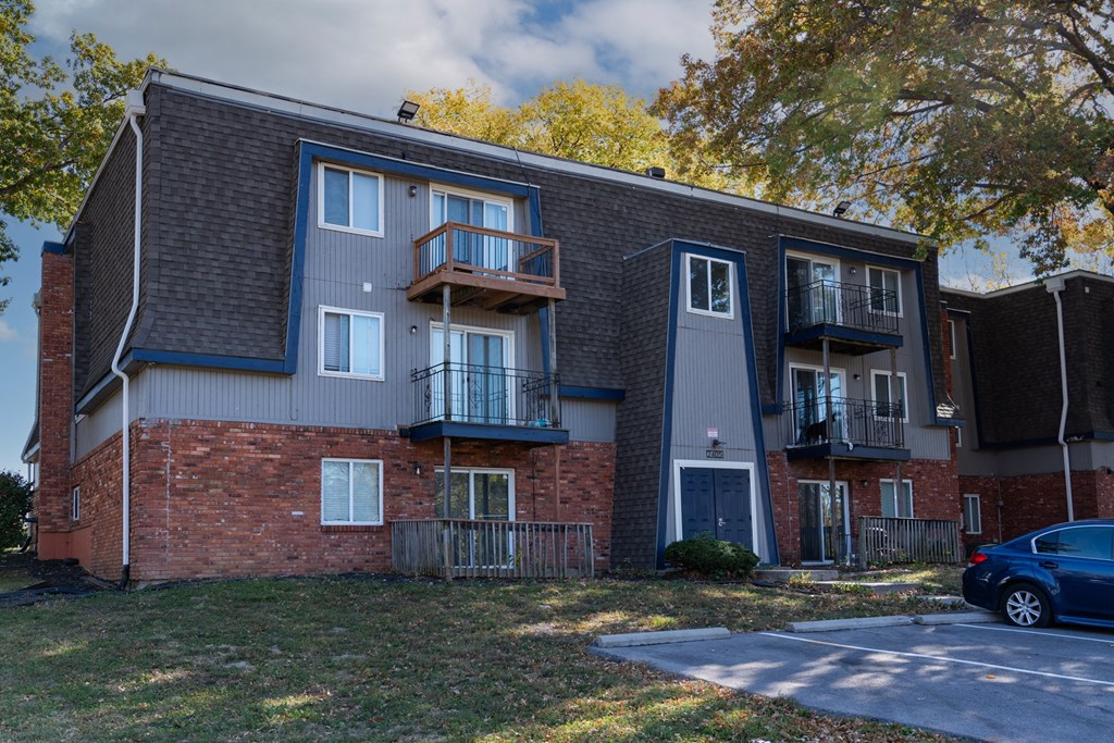 an apartment building with three balconies and a car parked in front