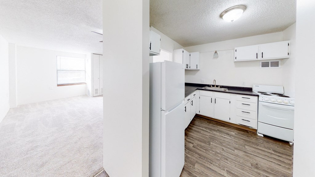 an empty kitchen with white appliances and white cabinets