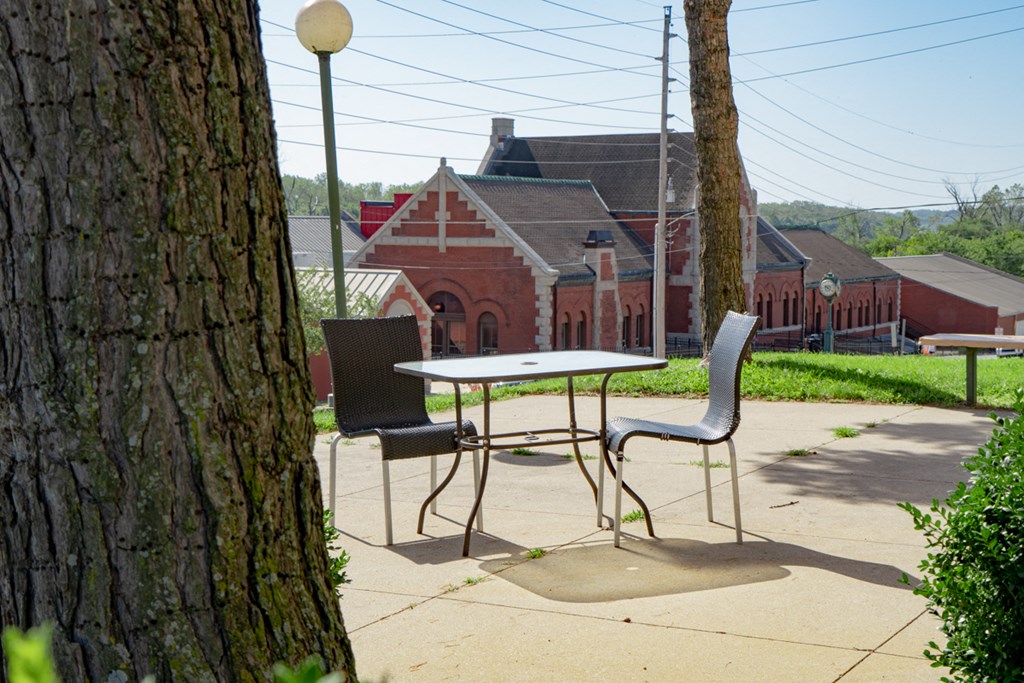 a table and chairs on a sidewalk next to a tree