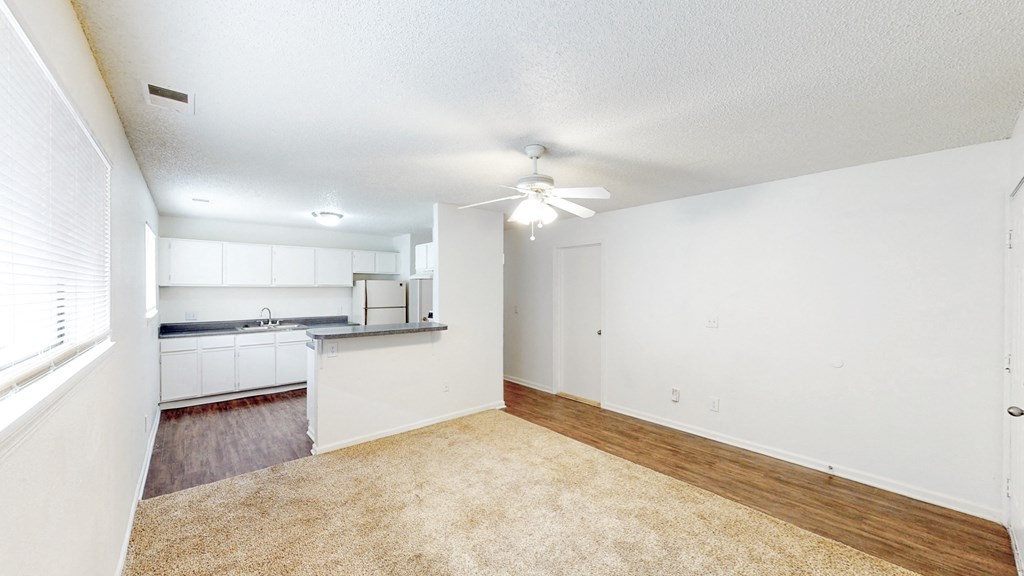 an empty living room and kitchen with a ceiling fan