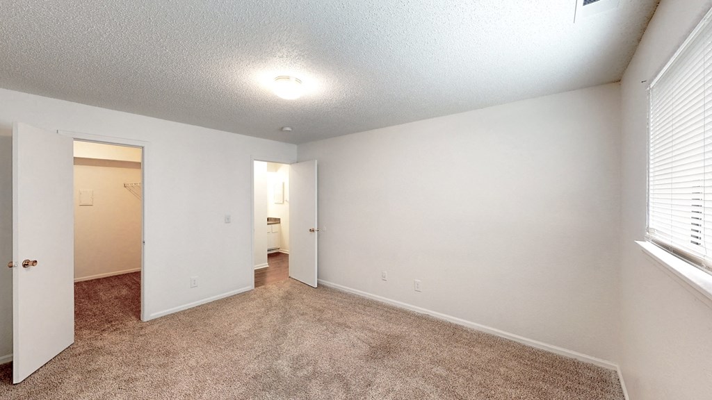 an empty room with carpet and a door to a bathroom