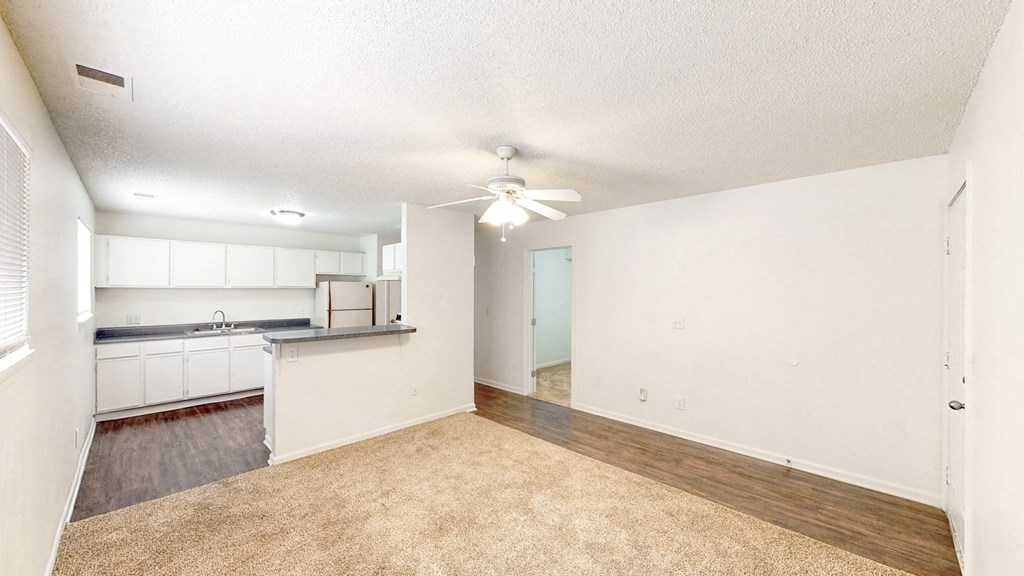 an empty living room and kitchen with a ceiling fan