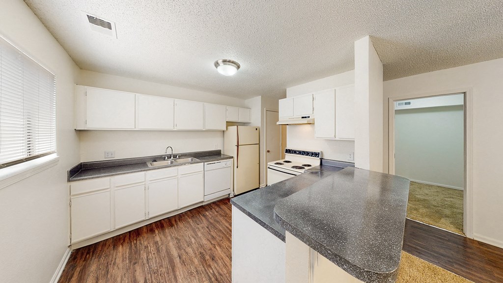 an empty kitchen with white cabinets and a counter top