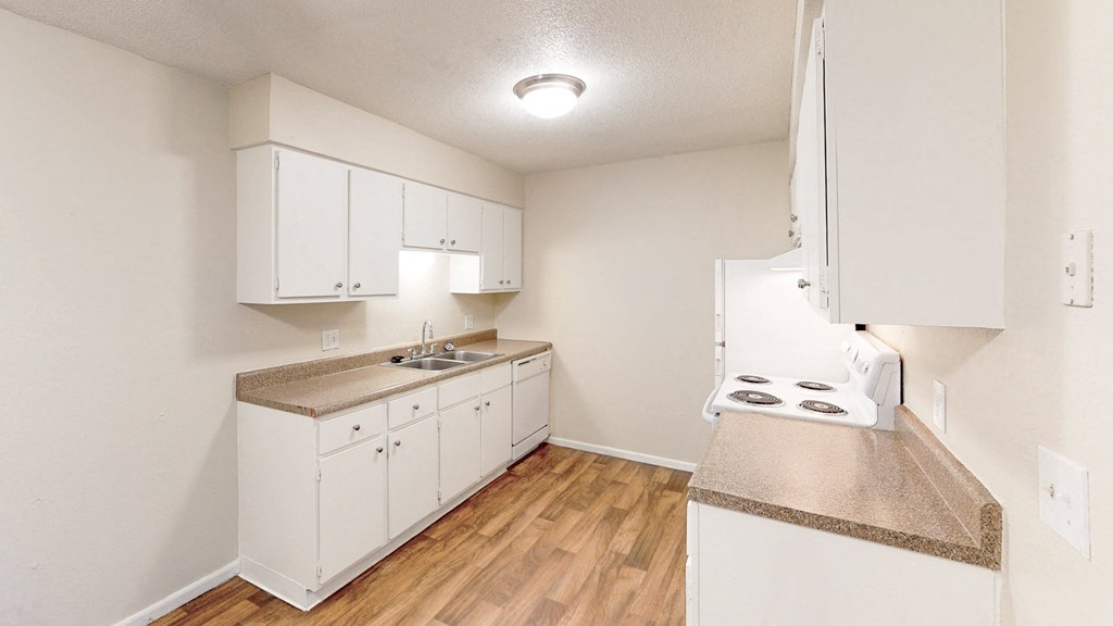 an empty kitchen with white cabinets and a counter top