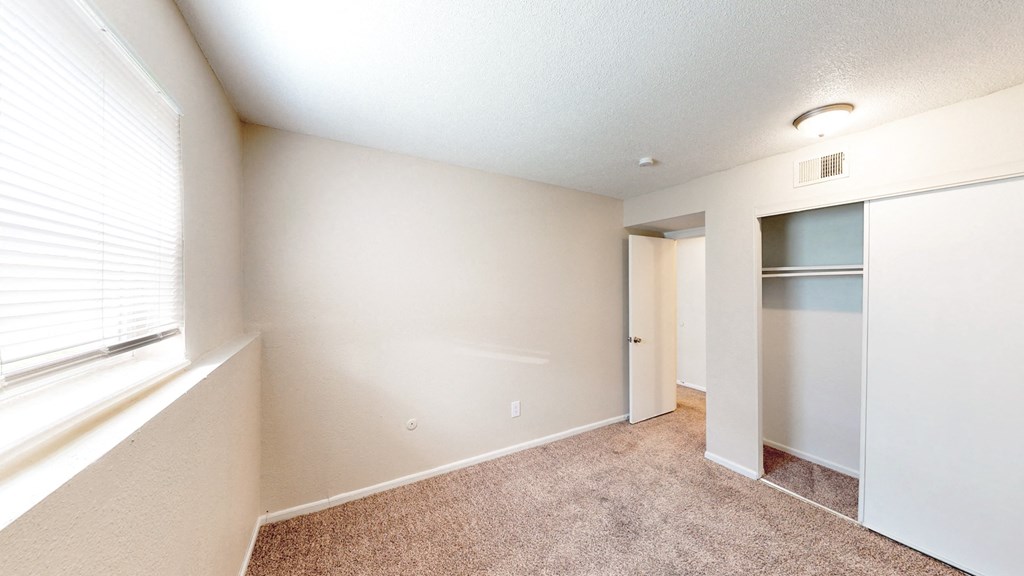 an empty room with a large window and a closet