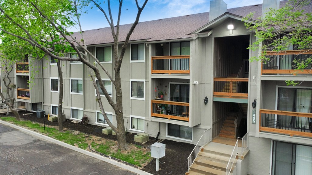 an exterior view of an apartment building with stairs and trees