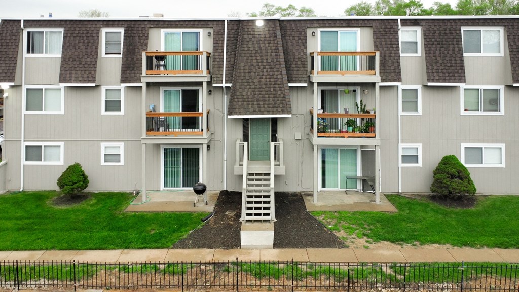 an exterior view of an apartment building with stairs and grass