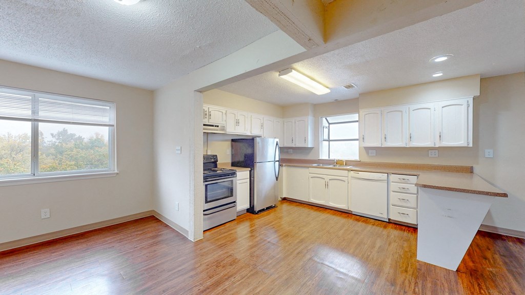 an empty kitchen with white cabinets and a wood floor
