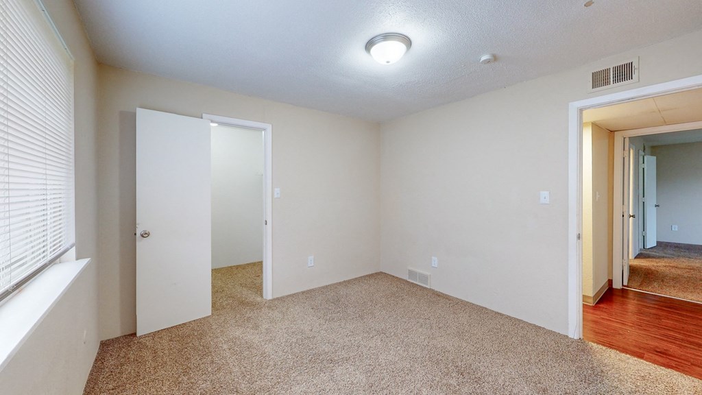 an empty living room with a door to a hallway and a window