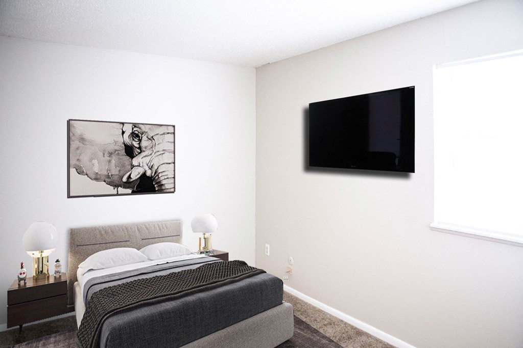 a bedroom with a bed and a television on the wall