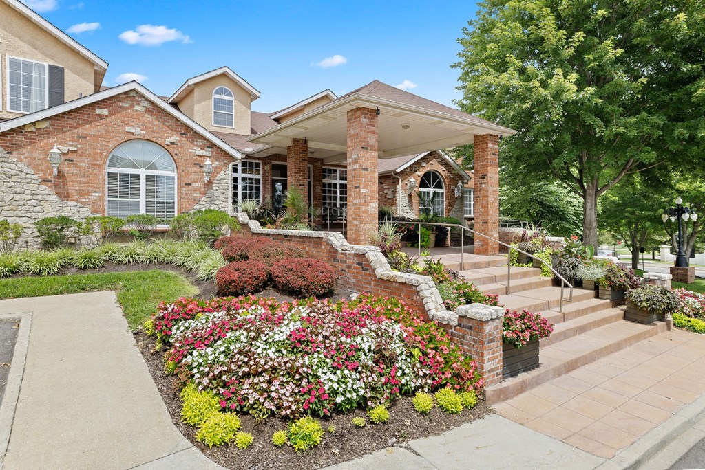 the front of a brick house with a flower garden in front of it