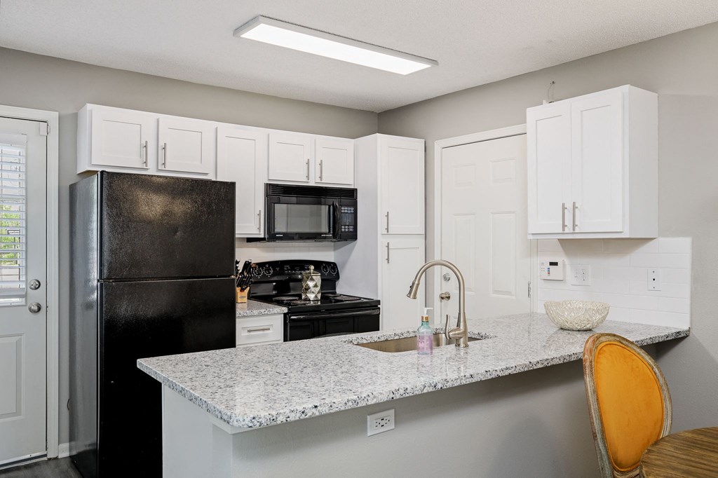 a kitchen with a granite counter top and a black refrigerator