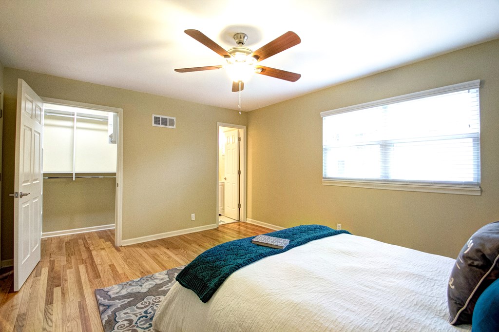A bedroom with a bed, a ceiling fan, and a window.