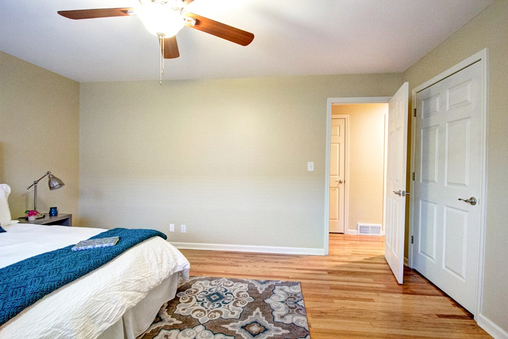 A bedroom with a bed, ceiling fan, and a rug.