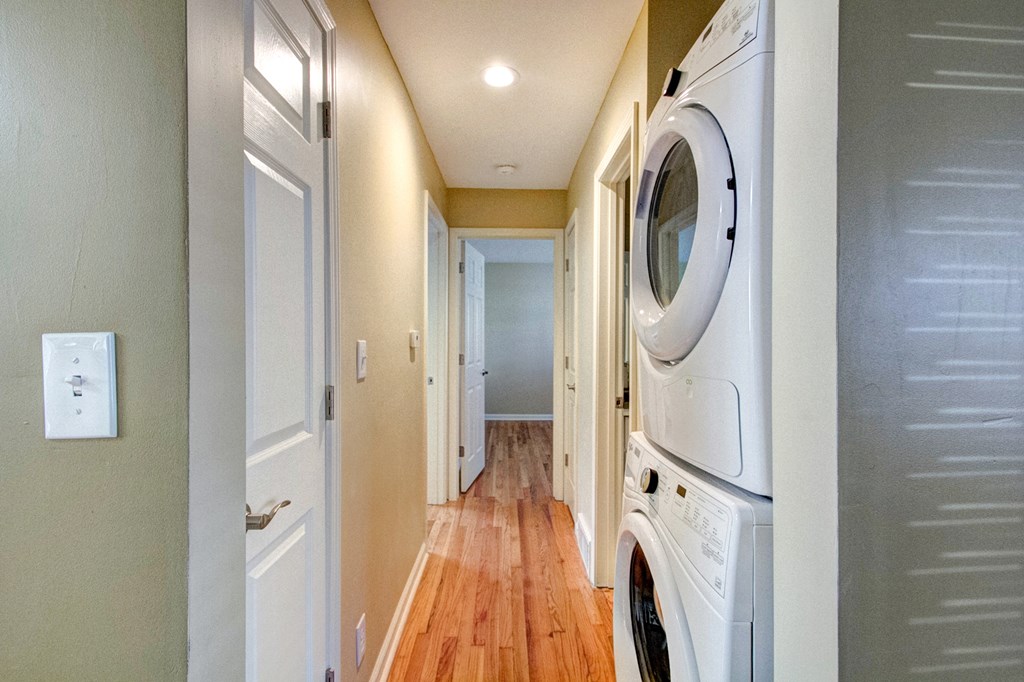 A long hallway with a washer and dryer on the side.