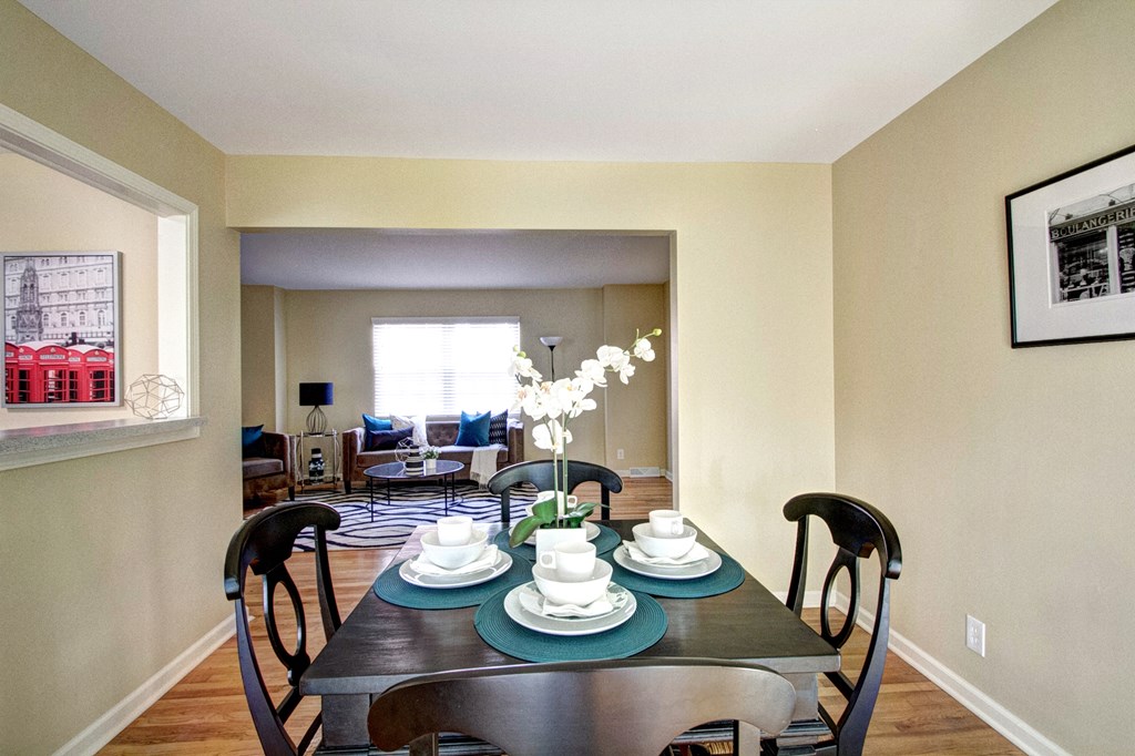 A dining room with a table set for two and a view of the backyard.